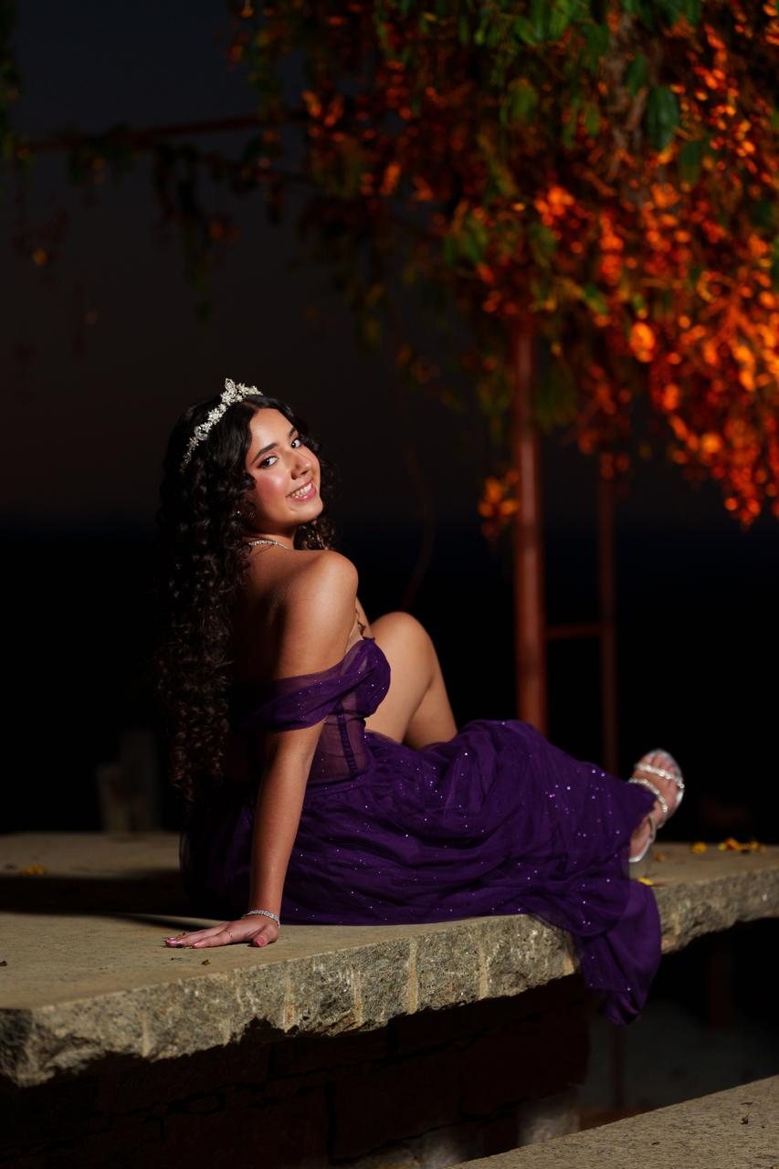 Lara com o vestido roxo no jardim ao entardecer